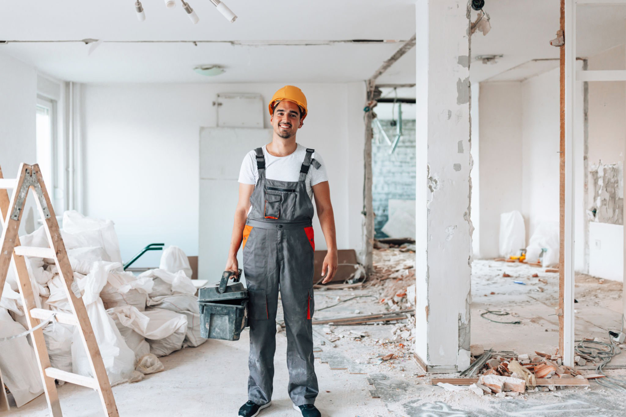 Capturé dans un portrait convaincant, un jeune ouvrier du bâtiment se tient avec assurance dans l'appartement en cours de rénovation, incarnant le dévouement et l'expertise.