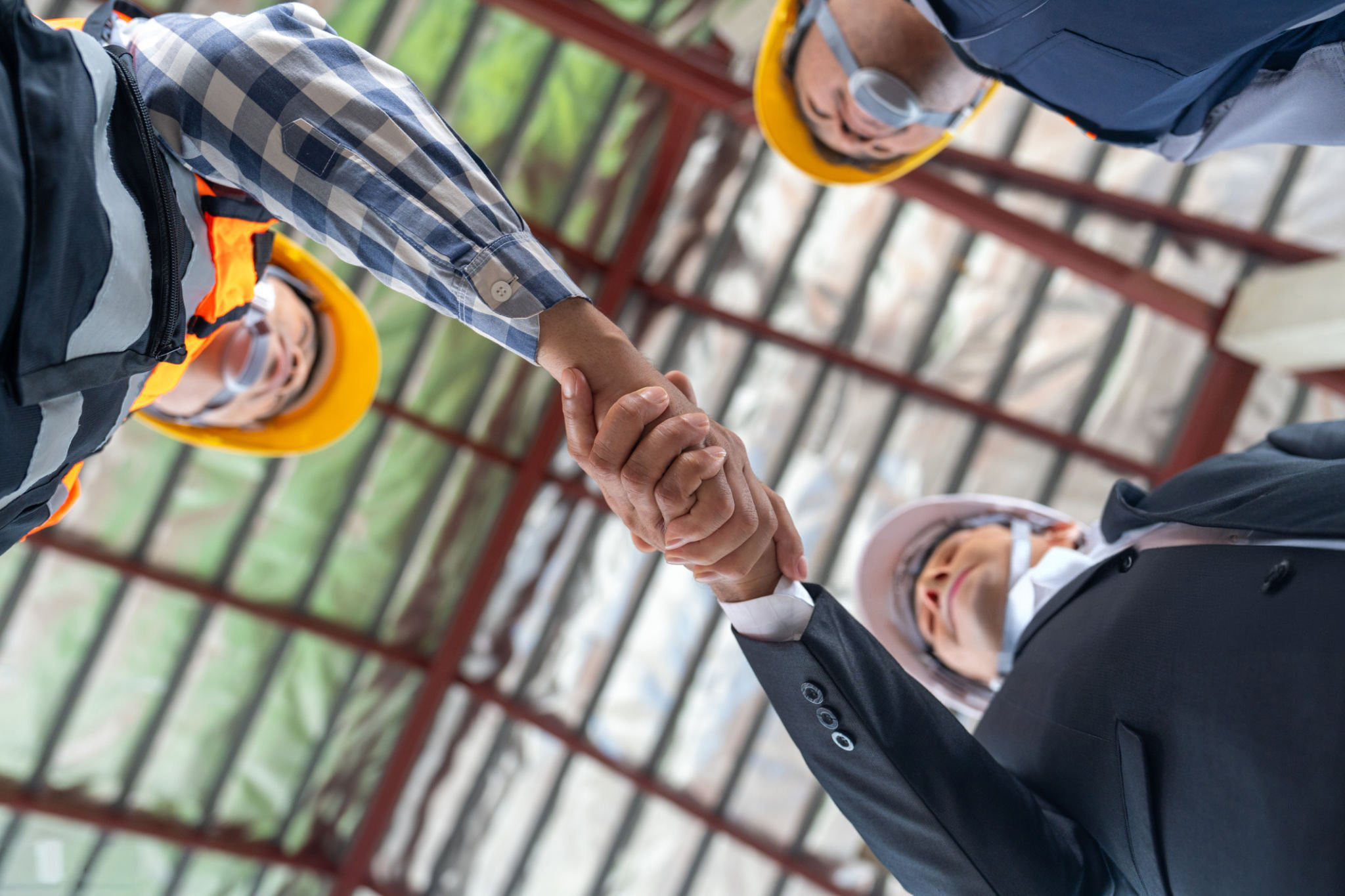 Travail d'équipe réussi dans le domaine de la construction, un ouvrier de la construction et un ingénieur civil se serrent la main sur un chantier de construction. Vue d'en bas.