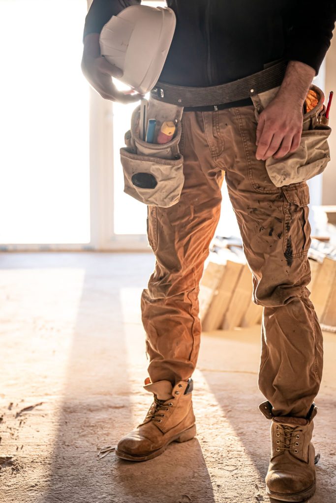 Un homme bâtisseur avec un casque de protection dans les mains sur un chantier de construction, partie du corps.